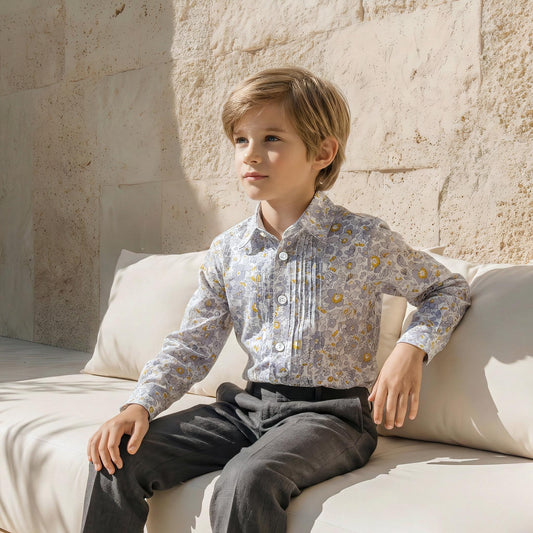May include: A light blue floral print button-down shirt with a pleated front, paired with dark gray pants. The shirt features a delicate pattern of yellow and gray flowers. The outfit is suitable for a formal occasion.