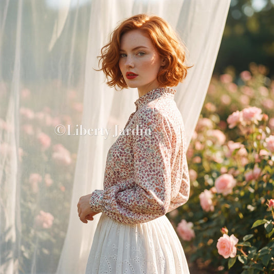 May include: A long-sleeved blouse featuring a small-scale floral print in shades of pink, blue, and green with a high ruffled collar, paired with a white eyelet skirt. The text Liberty Jardin is visible on the blouse. The garment has cuffed sleeves.